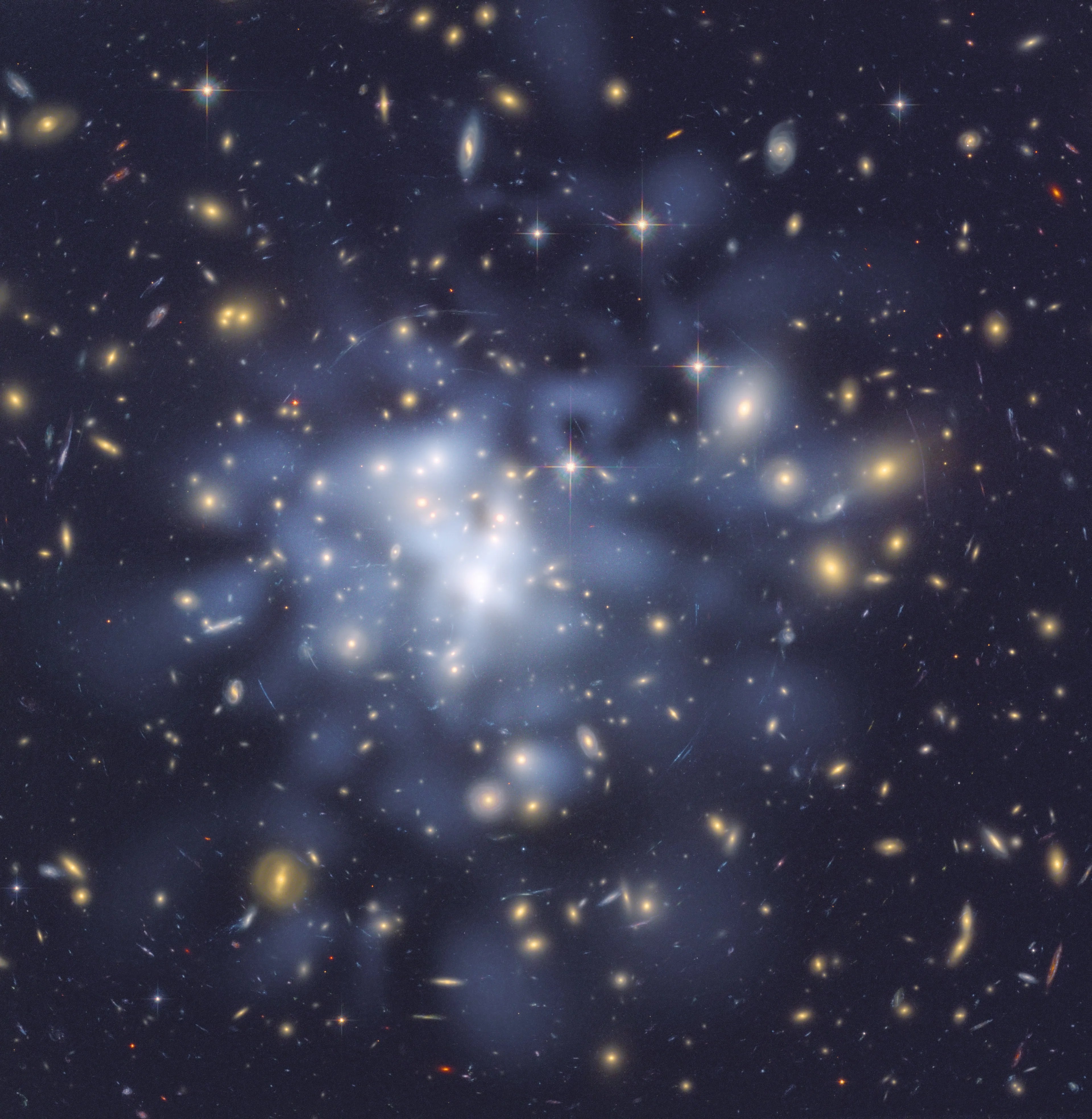 Yellow and white colored galaxies litter the frame. Blue, blue-white, and white clouds denote the distribution of dark matter, which is concentrated just to the left of center.