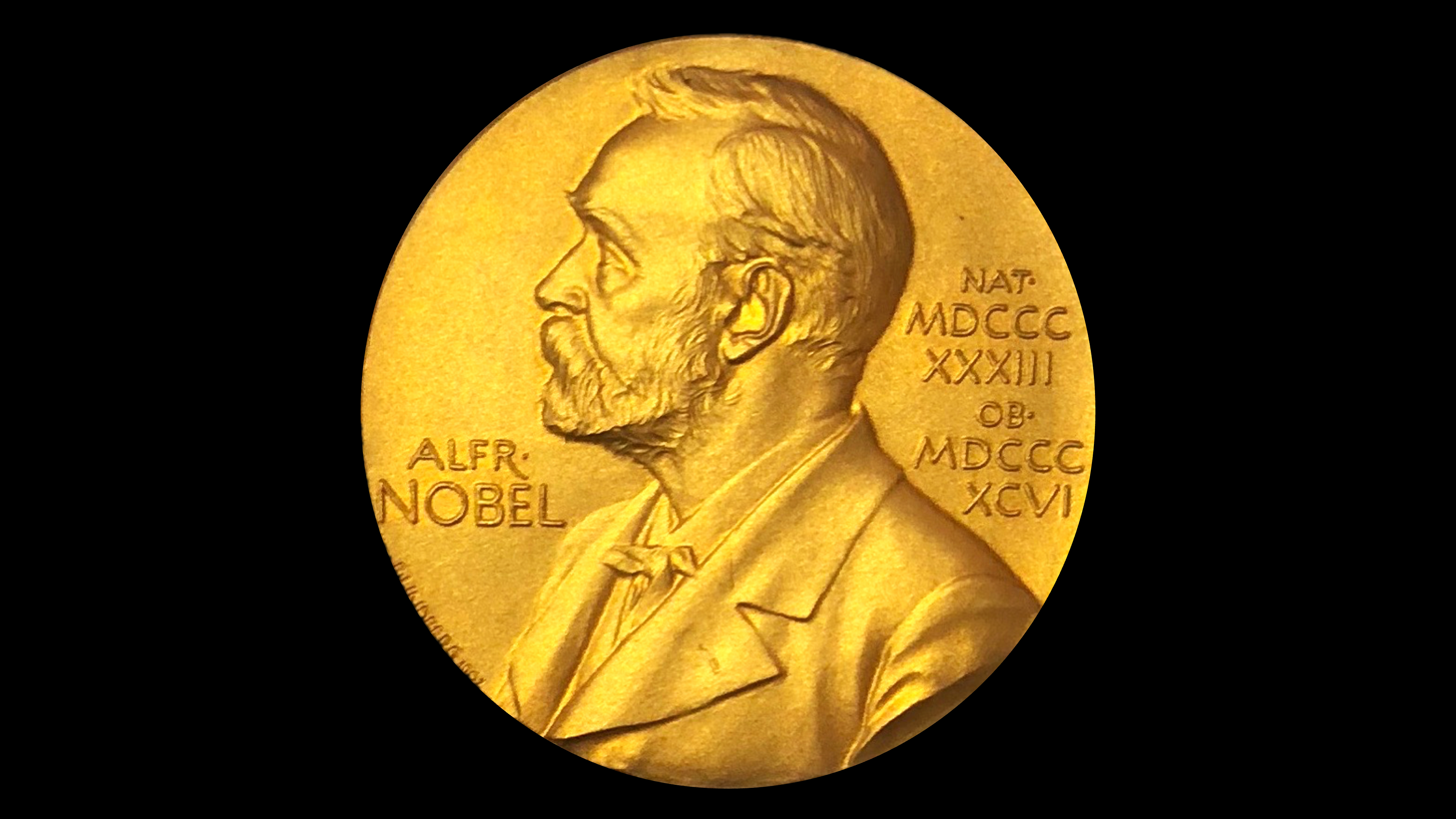 A circular, gold Nobel Prize Medal sits against a black background.