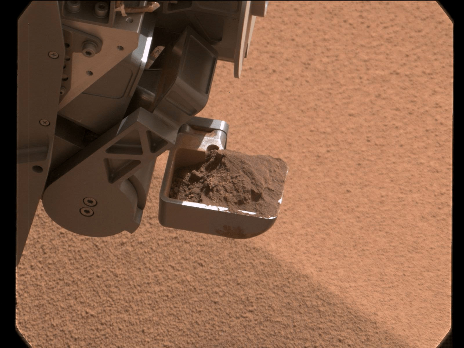 Closeup of Mars rover scooping up a sample of surface material
