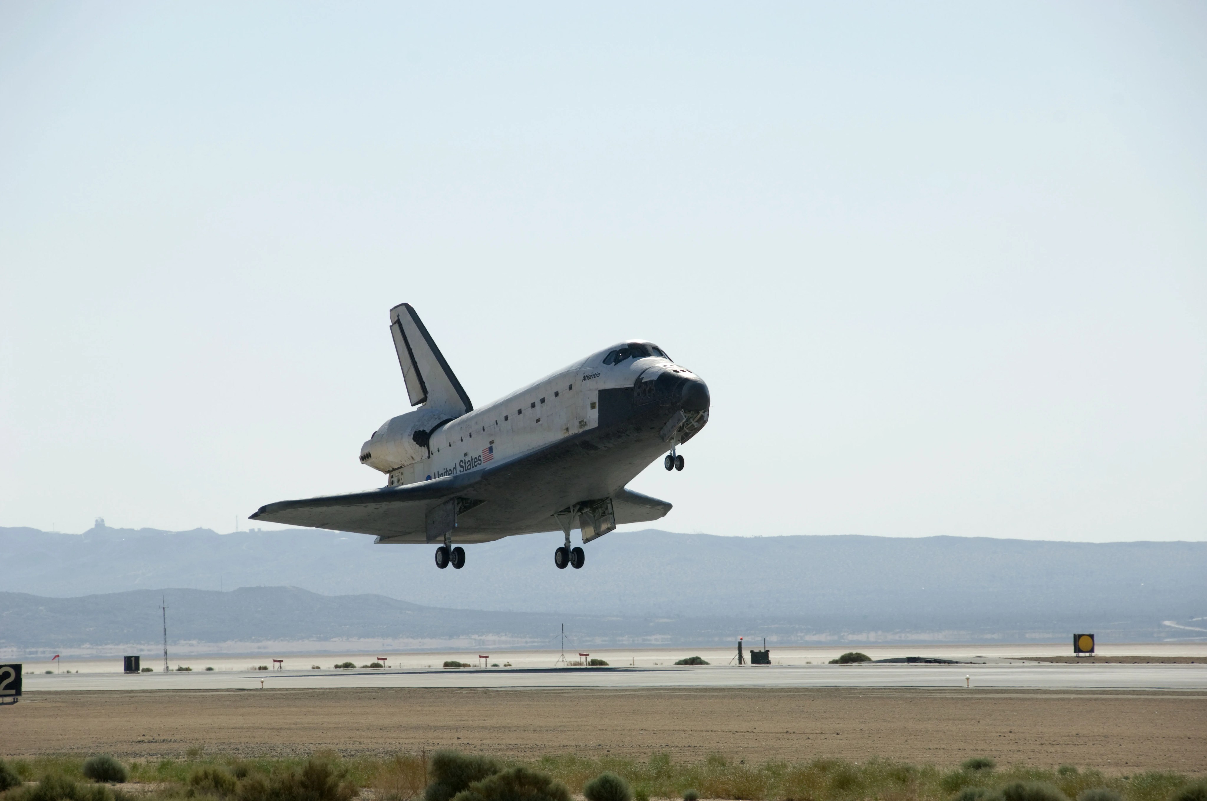The space shuttle floats a few feet above the runway as it is about to land.
