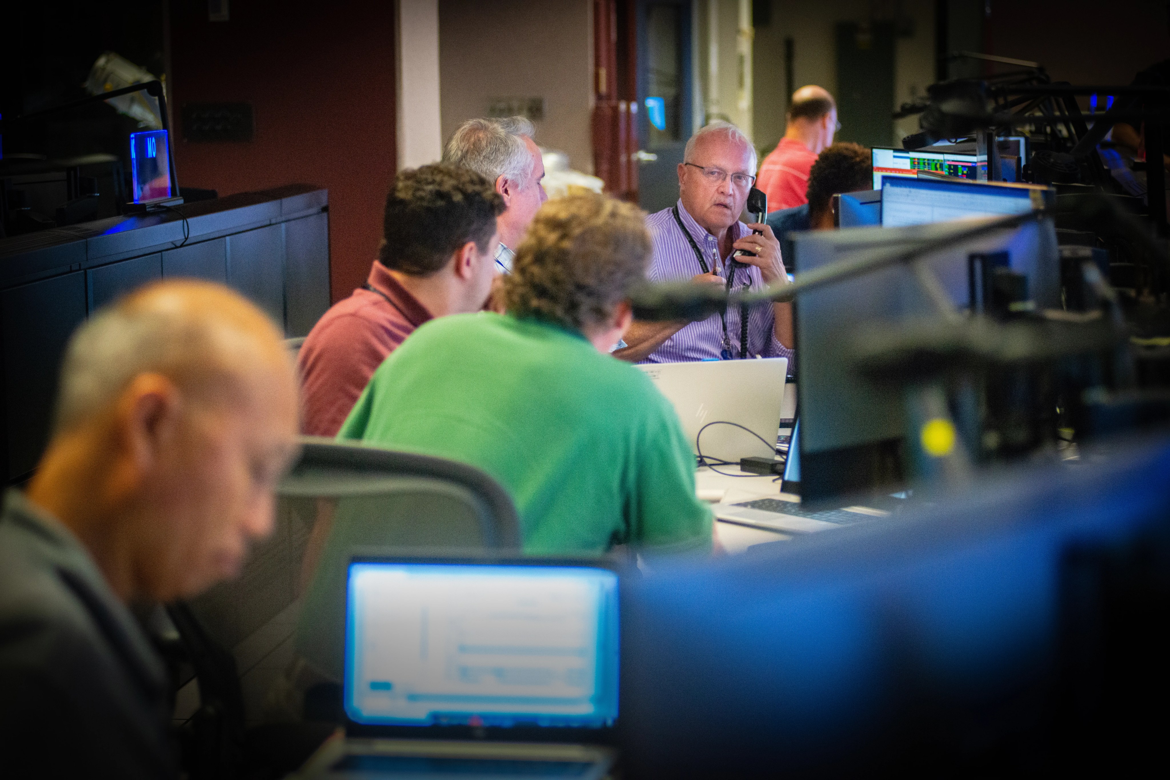 A row of people talking at a console of computers in the Hubble Space Telescope Operations Support Room