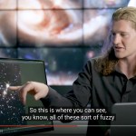 Scientist sits and points to a screen with a Hubble image while he discusses the science.