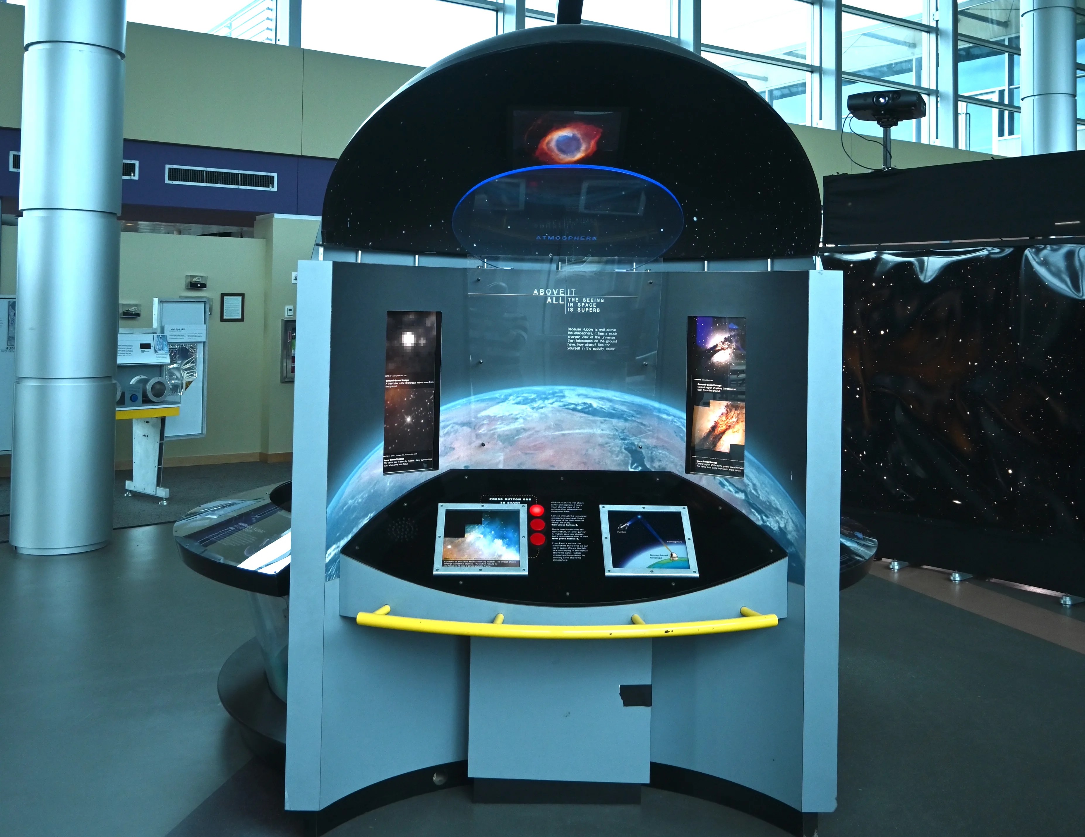 The backside of the HST traveling exhibit is shown that explains why scientists want a telescope above the blurring affects of Earth's atmosphere.