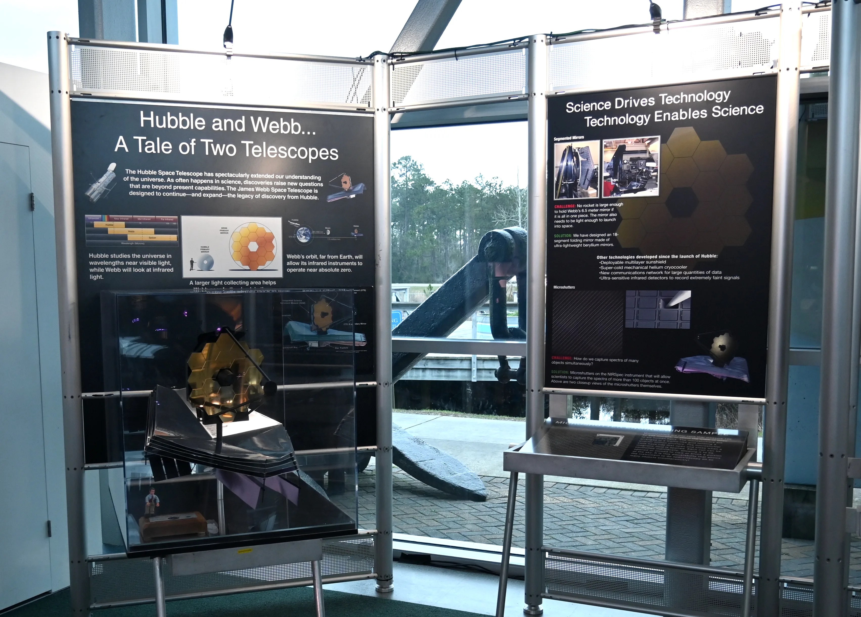 A scaled spacecraft model and explanatory panels on display describing the James Webb Space Telescope