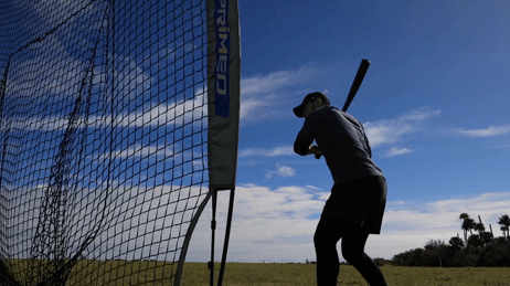 A moving GIF that shows Paul Dejong hitting baseballs into a net, showing his bat to the viewer, and catching baseballs in front of a large building with the NASA insignia on it.