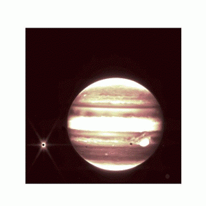 The background of space is black. Jupiter is on the right with bands of brown and white. On the left, the moon Europa is a very small, dark circle with a bright spot of light around with, with six diffraction spikes.