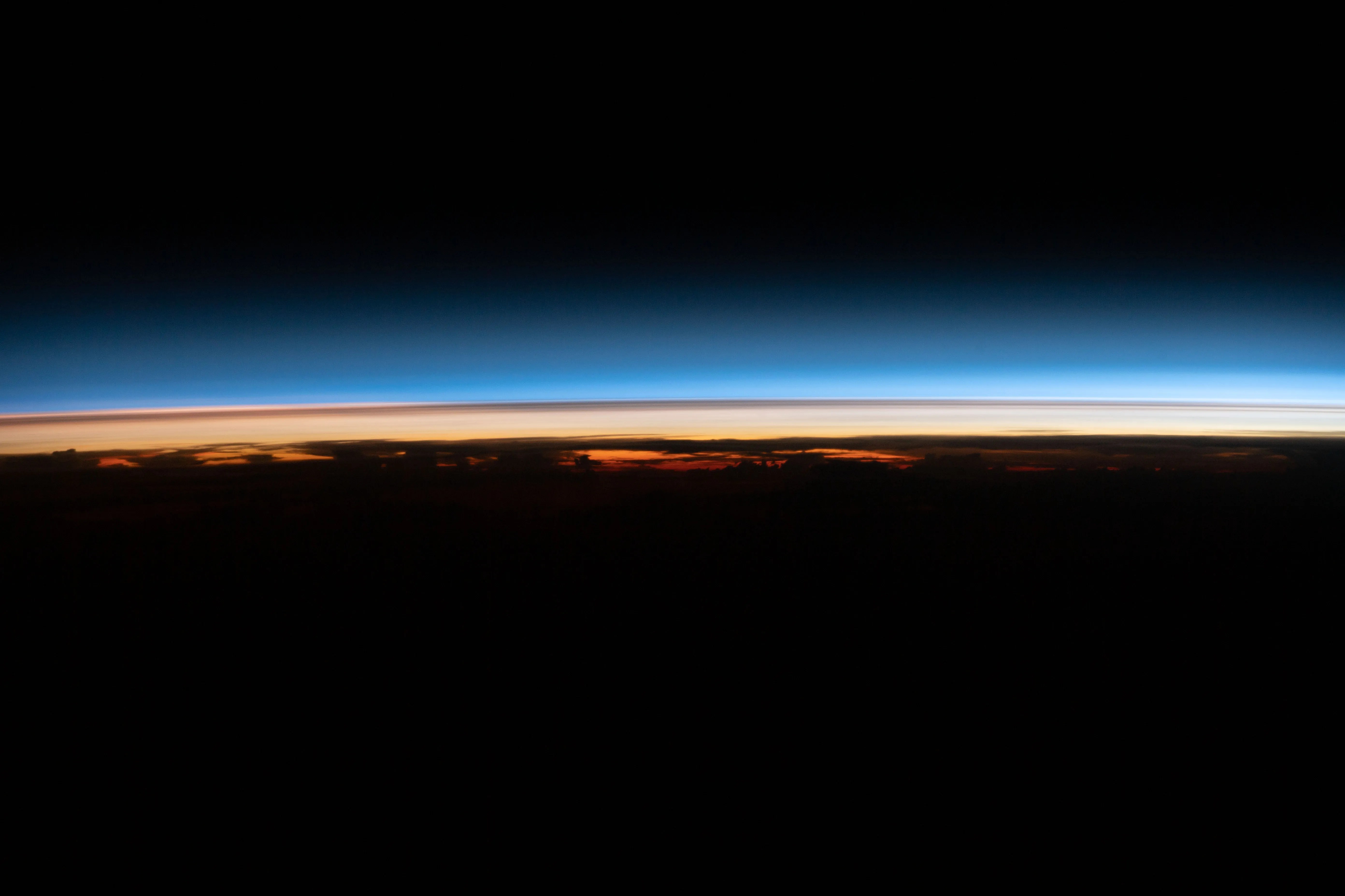 In this photo captured from the ISS in March 2022, the Earth’s limb is shown with a dark thin layer sitting in the bluish color of the stratosphere. This dark thin layer is remnants of the Tonga volcanic plume, lingering in Earth’s stratosphere months after the eruption that occurred in January 2022.