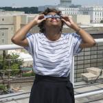 A woman looks up at the sky while wearing eclipse glasses.