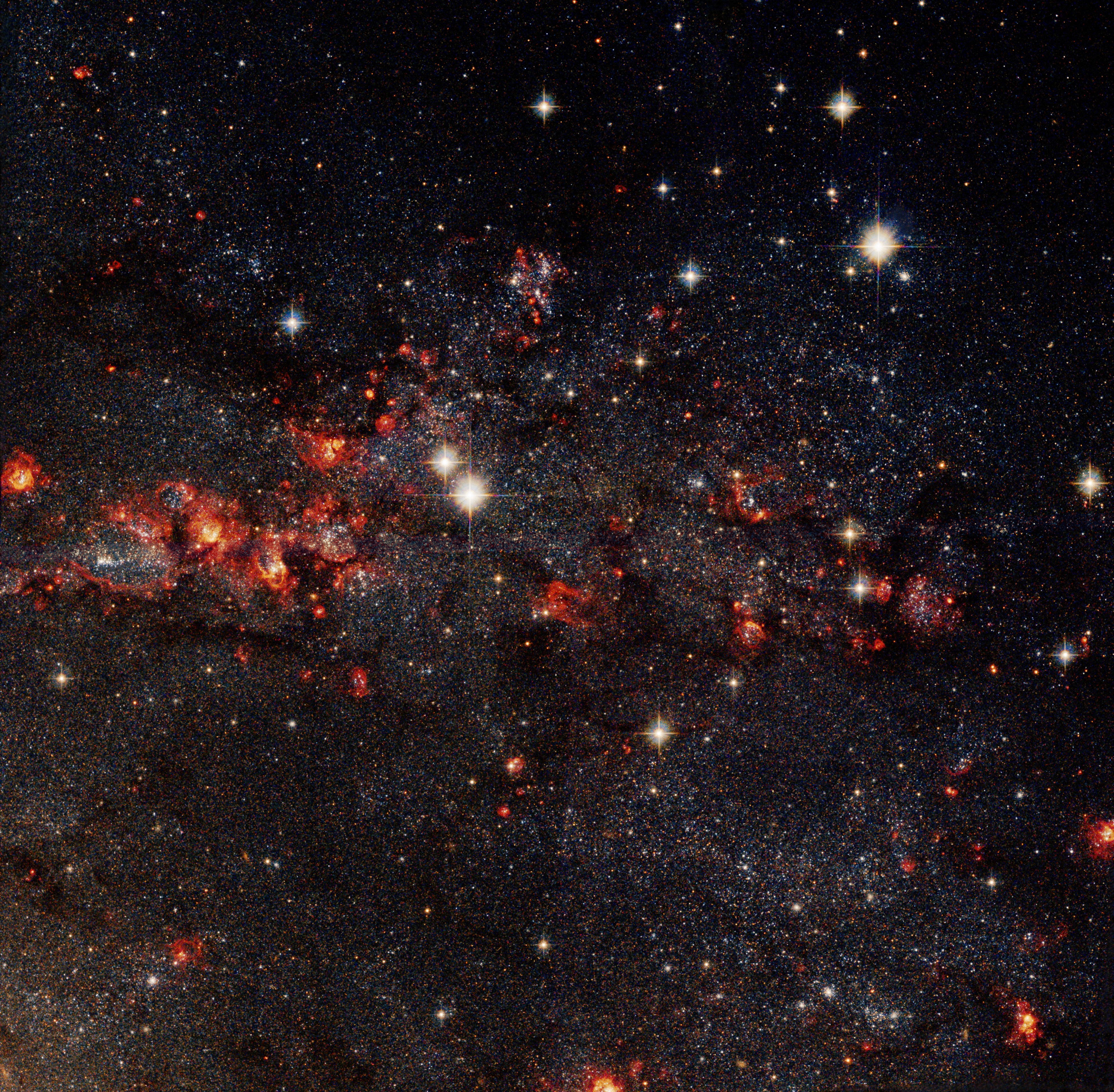 On the left side of the image is a spiral galaxy, on the right the inset shows a zoom in with dark red stars and dust and gas.