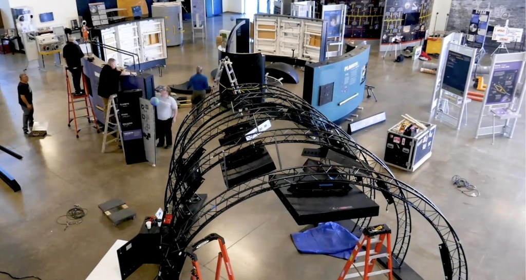 A birds eye view of a team of technicians putting together the Hubble traveling exhibit.