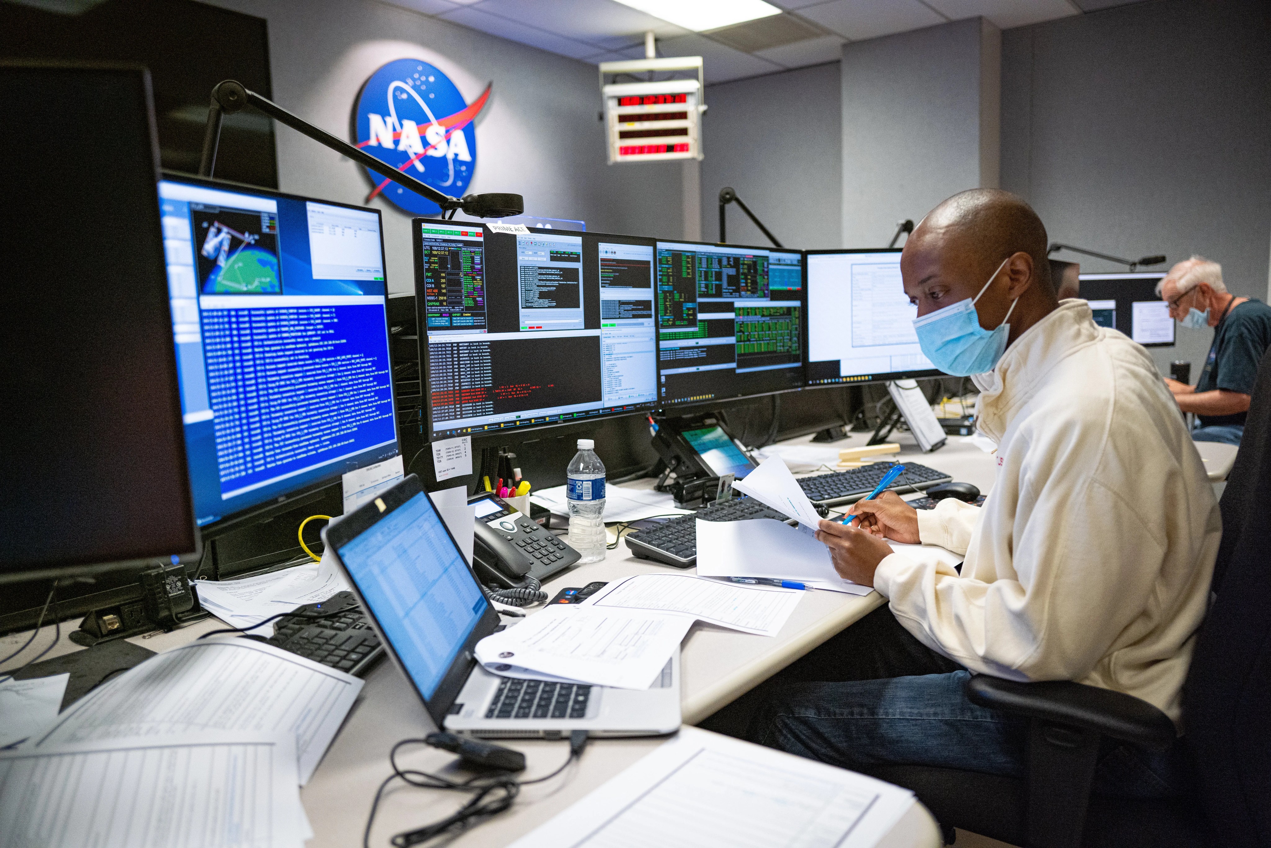 Man at computer desk with many screens working on Hubble