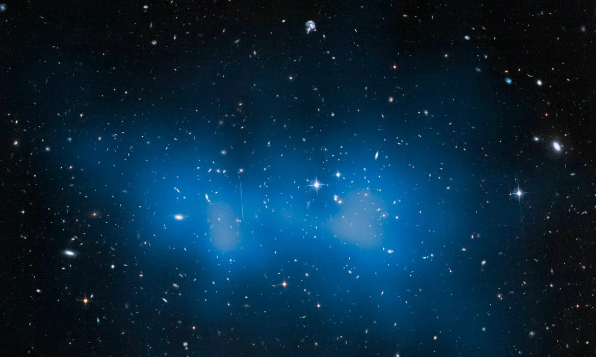 A massive galaxy cluster full of galaxies of all shapes and sizes, which seem to be surrounded by a bright blue haze.