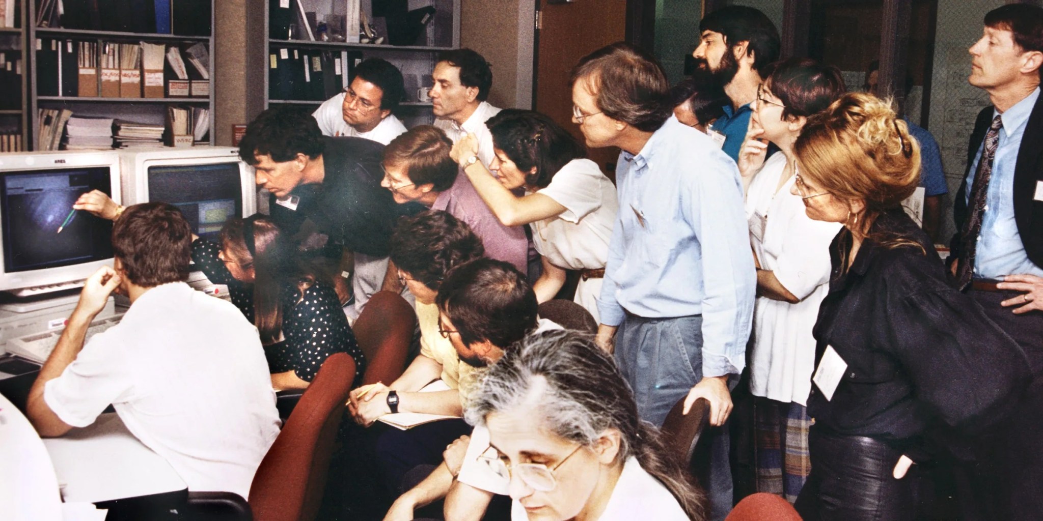 people crowd around a computer monitor