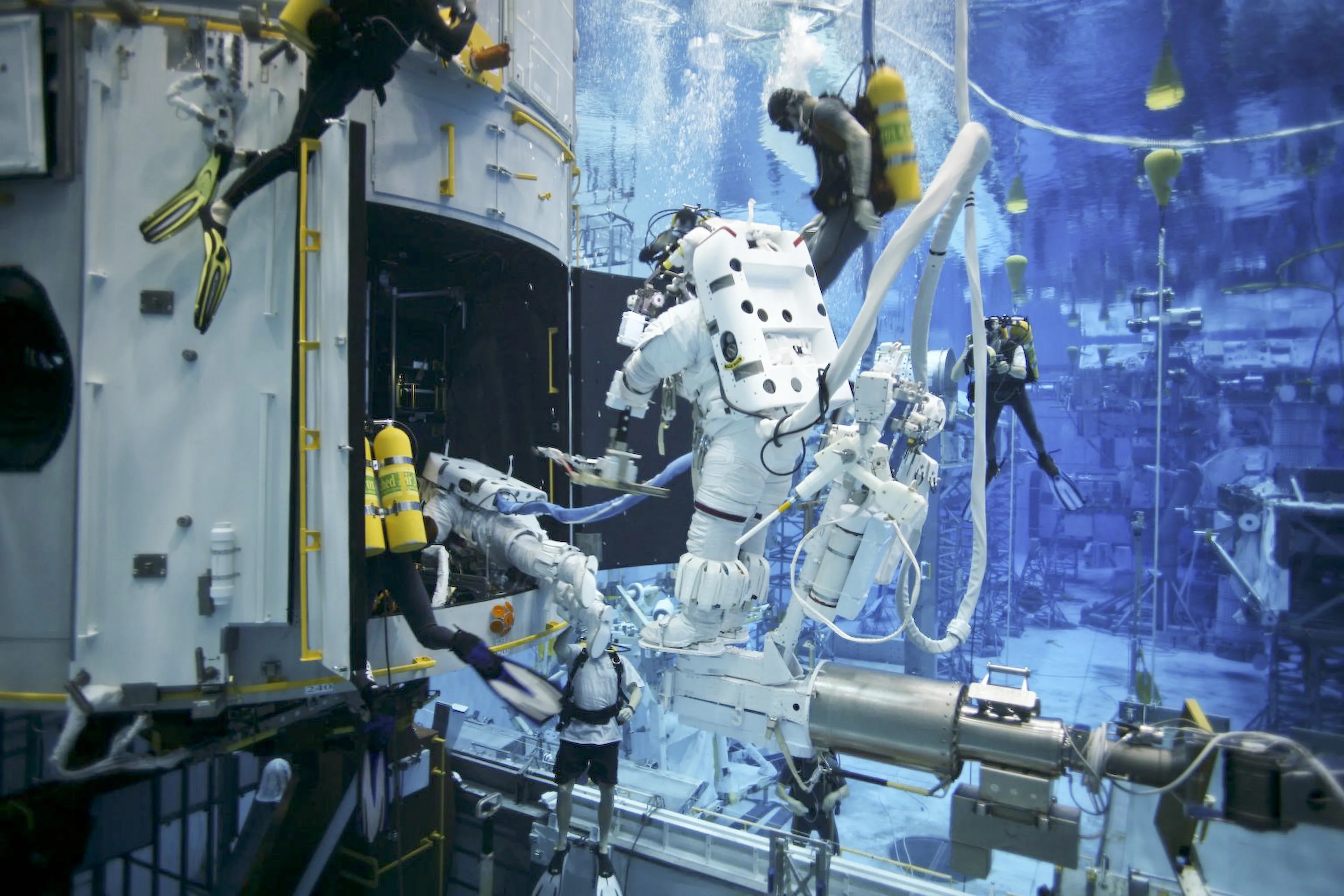 Astronauts practice in the NBL under the watchful eye of NASA engineers and safety divers.