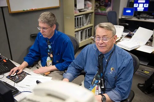 HST engineers Steve Leete, left, and Ron Sheffield of take a short break from making entries in the flight log while on console in the Flight Control Room at Johnson Space Center during Servicing Mission 4 to Hubble.