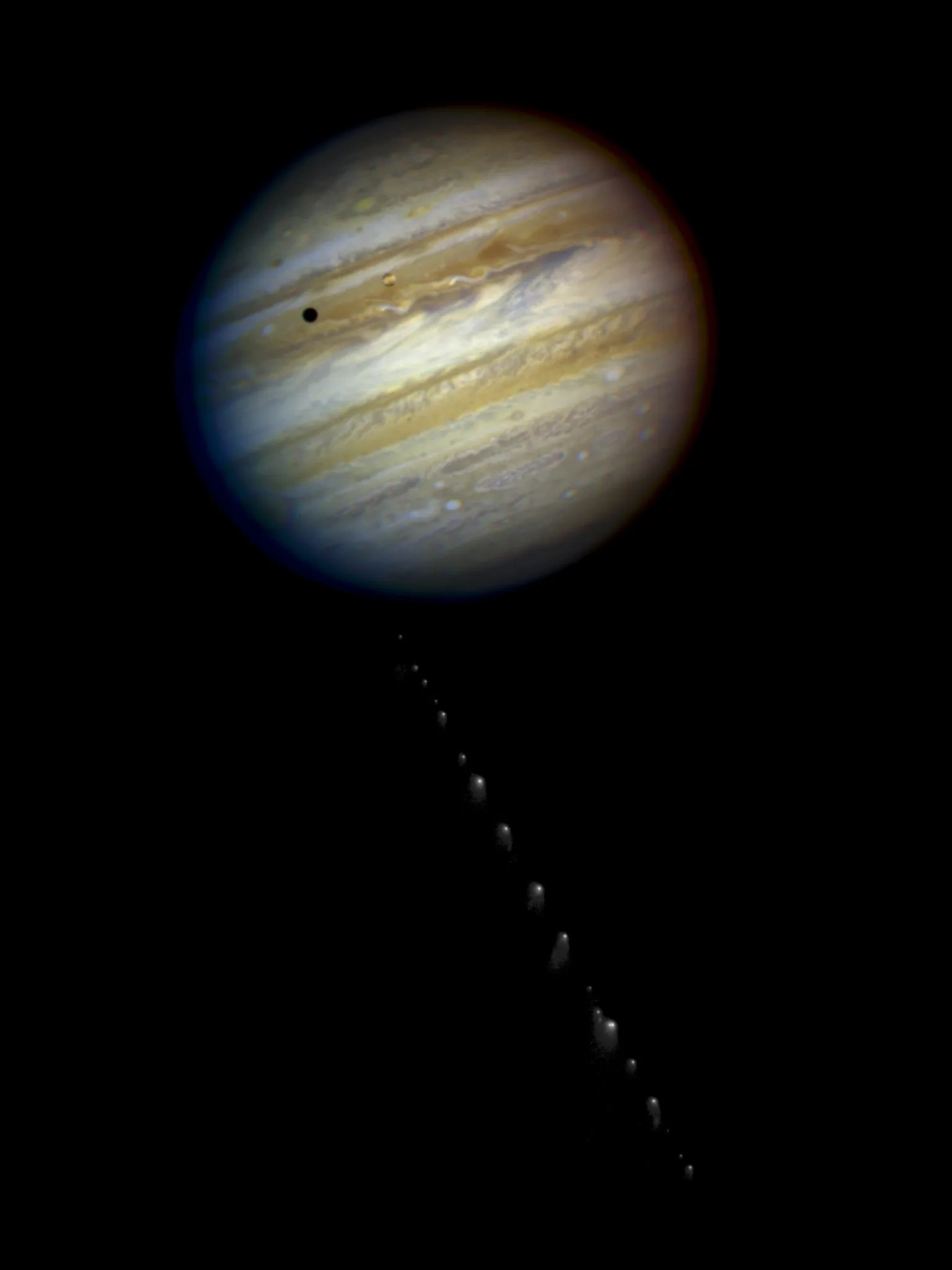 One of Jupiter's moons transits it and casts a shadow on Jupiter's atmosphere. The compilation of images as the comet approaches the planet from the bottom of the image forms a "trail".