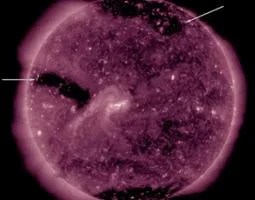 Three coronal holes appear as large dark areas which are identified with arrows in the still image.