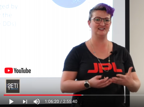 Christina Richey wearing a JPL shirt in front of a projector screen