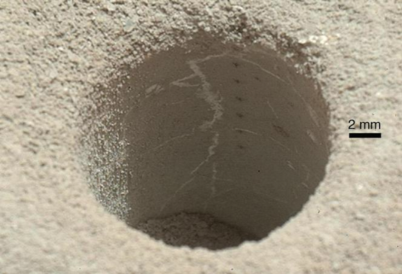 ChemCam laser analysis pits form a line inside the hole drilled by the Curiosity rover in the Sheepbed Mudstone. Each laser pit was produced by 30 laser shots, each with an energy of 14 milliJoules. The hole is about the size of a US dime and was shot from about 2.5 meters distance. Credit: NASA/JPL-Caltech/MSSS.