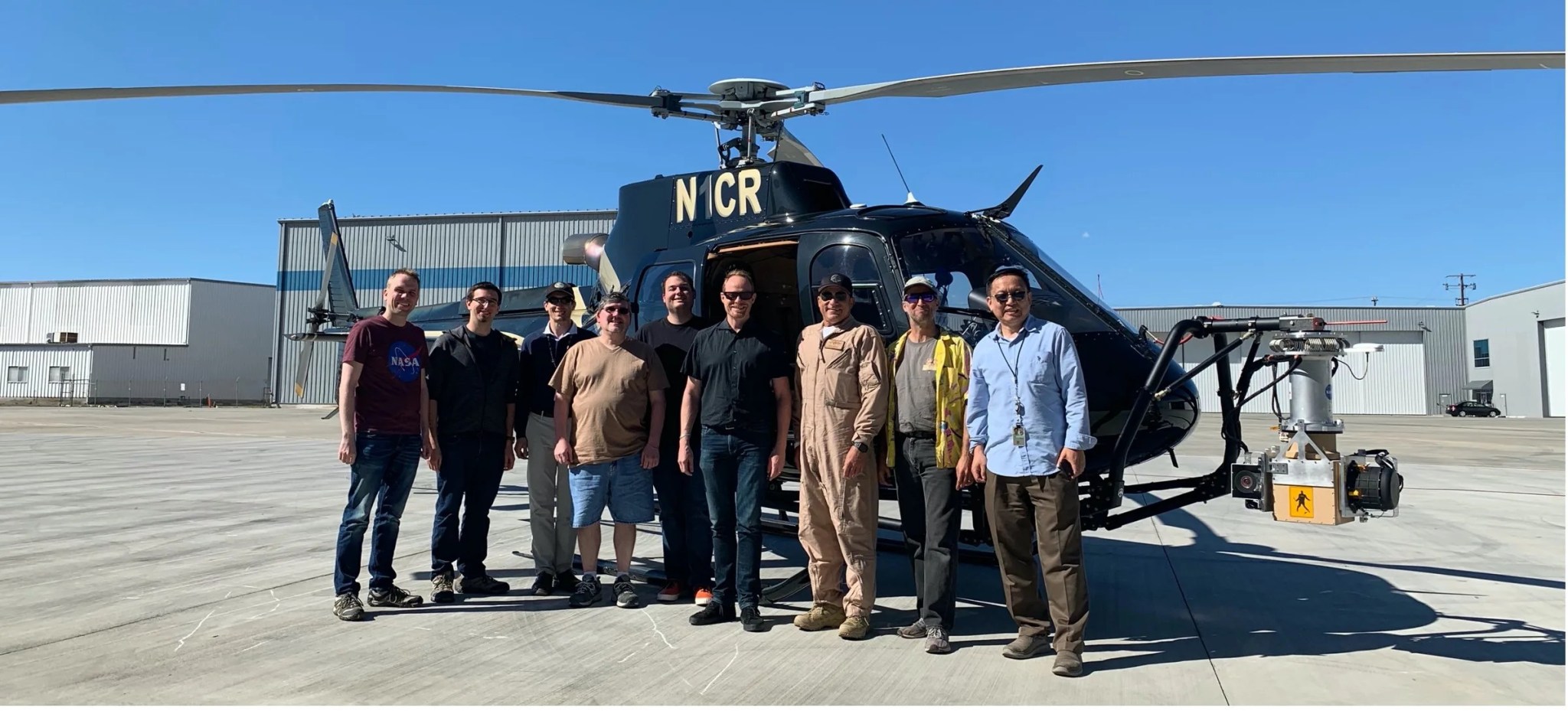 Photo of men standing in front of a helicopter