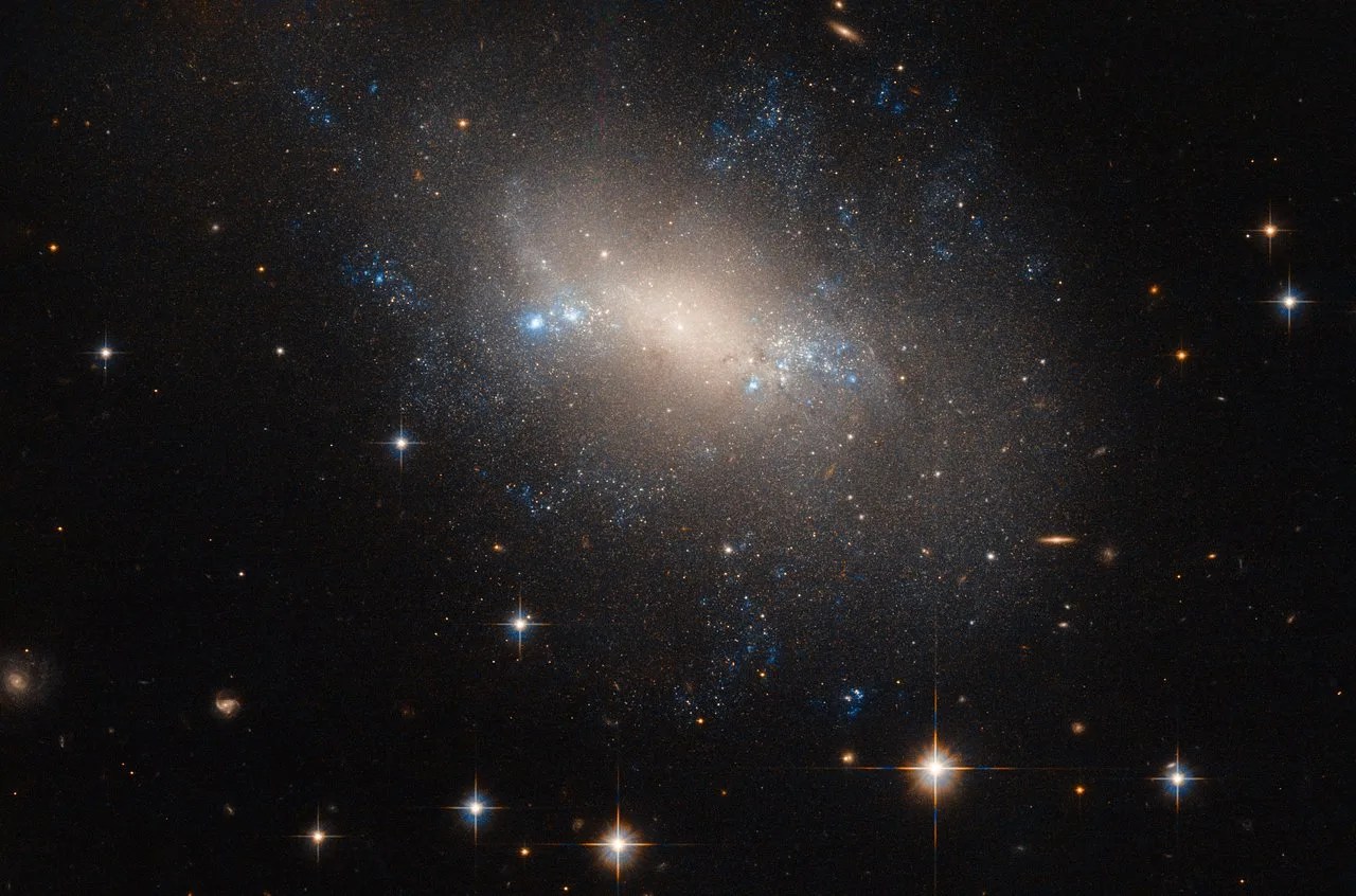An irregular galaxy with a glowing center surrounded by young, hot blue stars.