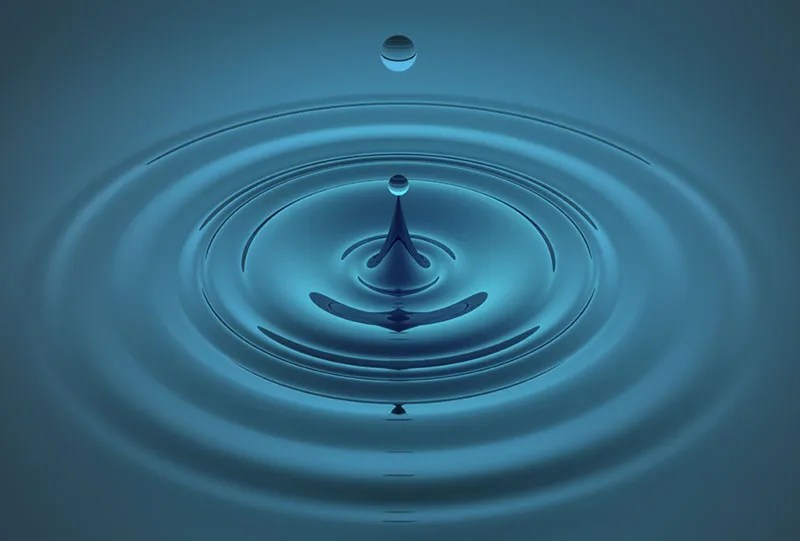 A photograph of a drop of water leaving ripples in a pool.