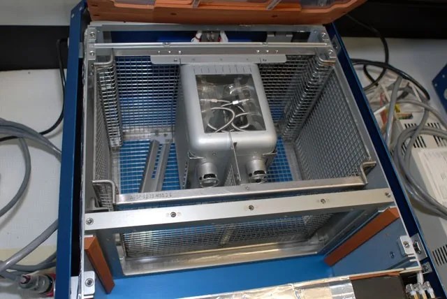 Blue metallic box with steel mesh and mechanical devices.
