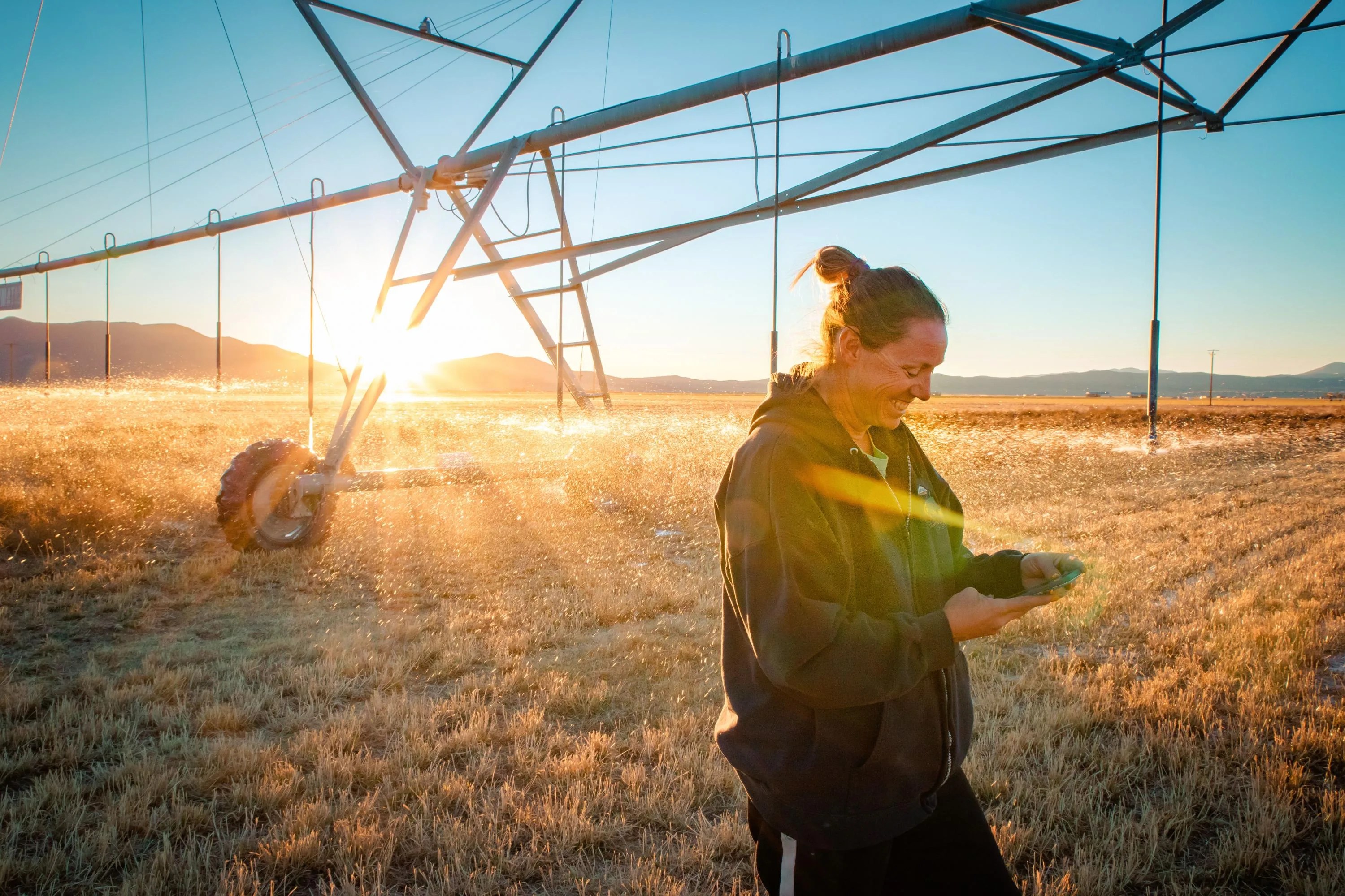 Woman standing in a crop field with irrigation equipment.