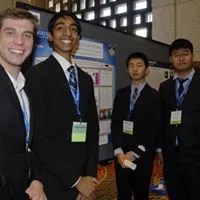 Group of male students assembled in front of scientific poster board