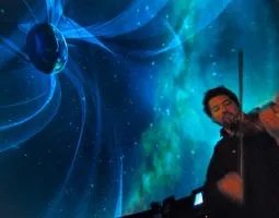 Man playing violin in front of projected earth image