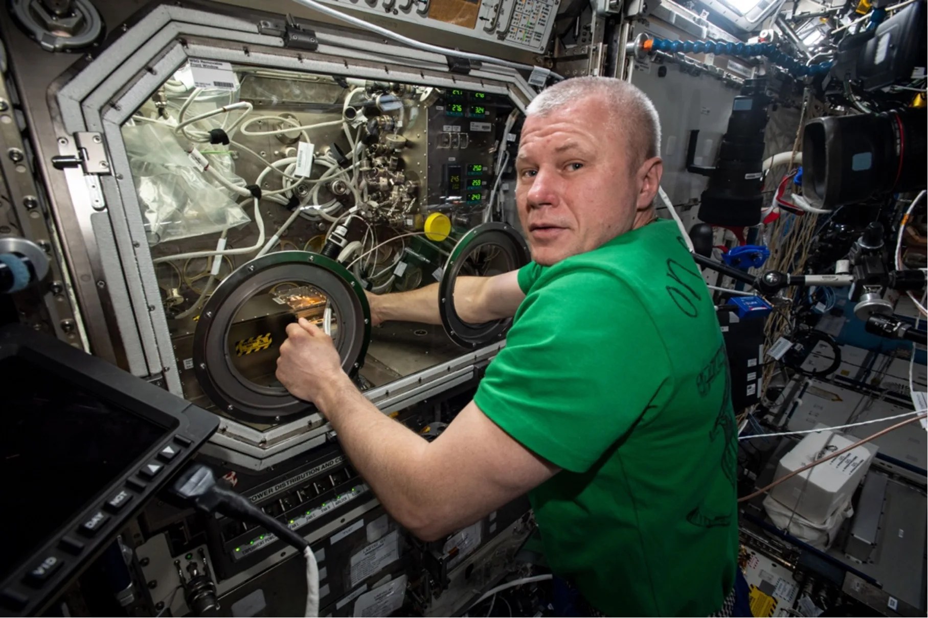 Weightless man with his arms inside two separate hole openings in glass-covered hardware.