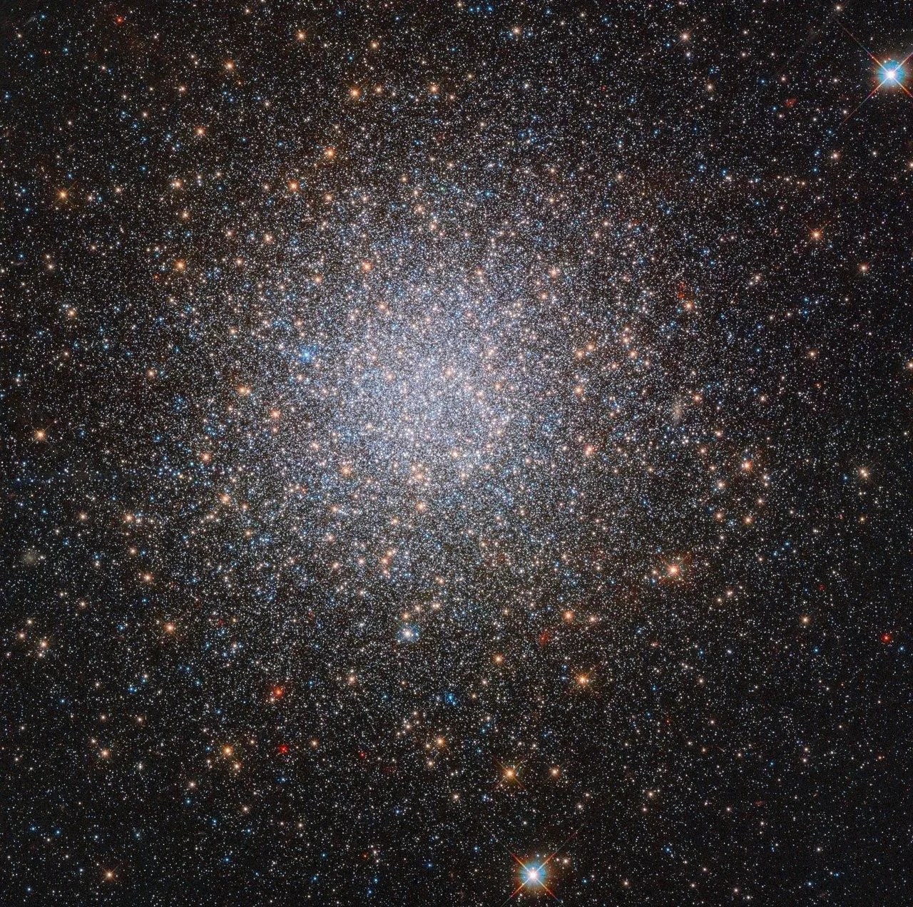 Huge grouping of countless stars, in colors red, blue, white, yellow. The closer to the center of the image, the brighter, and whiter it gets.