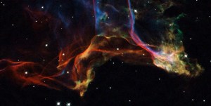 Wisps of red, yellow, blue and purple dust and gas dance all over the image. The blackness of space frames the image behind it.