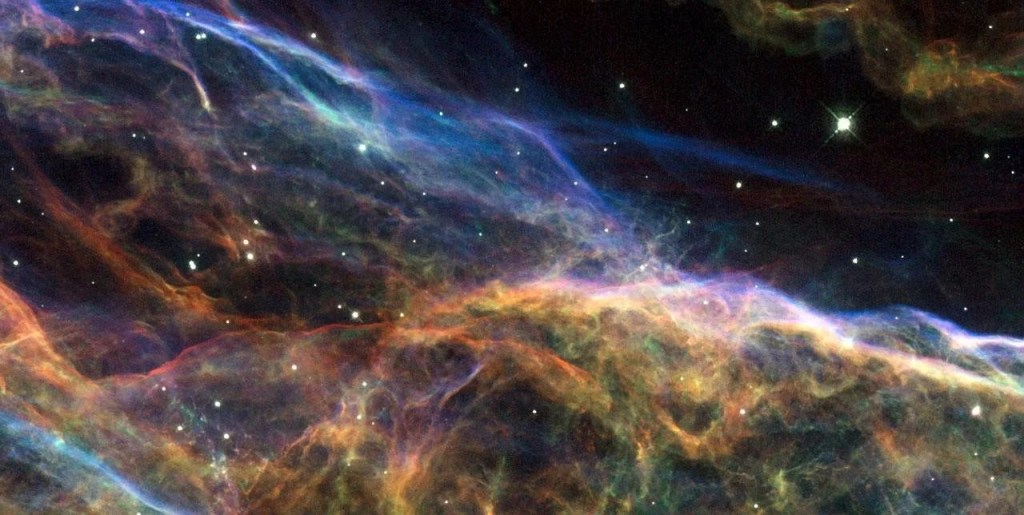 Bright yellow, red, and blue clouds of dust and gas form together near the bottom half of the image.