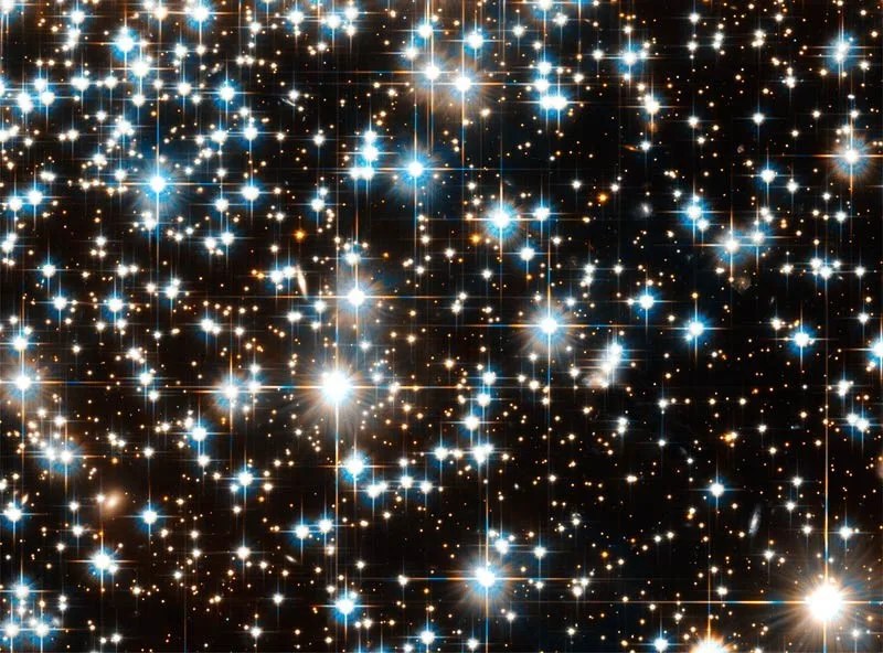 Dazzling, bright, white stars, some of which display cross-shaped spikes of light.