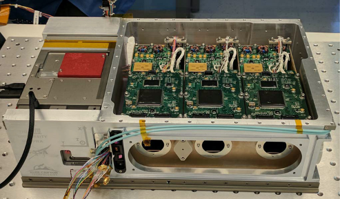 Photo of HaloSat hardware, a tan box on the left and electronic circuit boards and an Xray lens