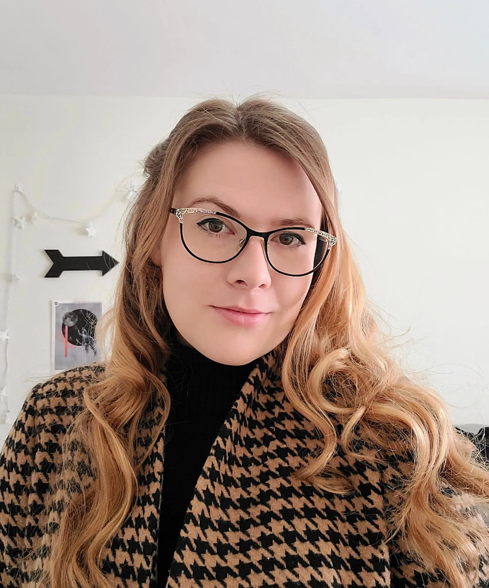 Elizabeth Tammi, a woman with glasses and long blonde hair, smiles at the camera for a selfie.