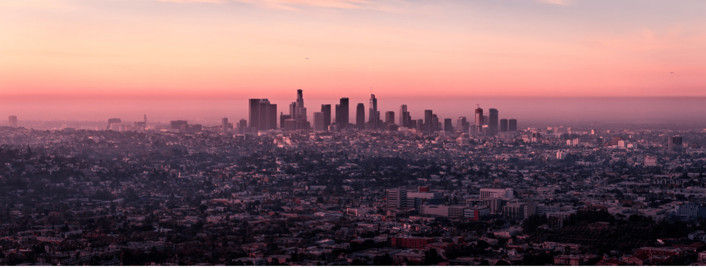 Photo of a hazy sunrise behind the LA landscape.