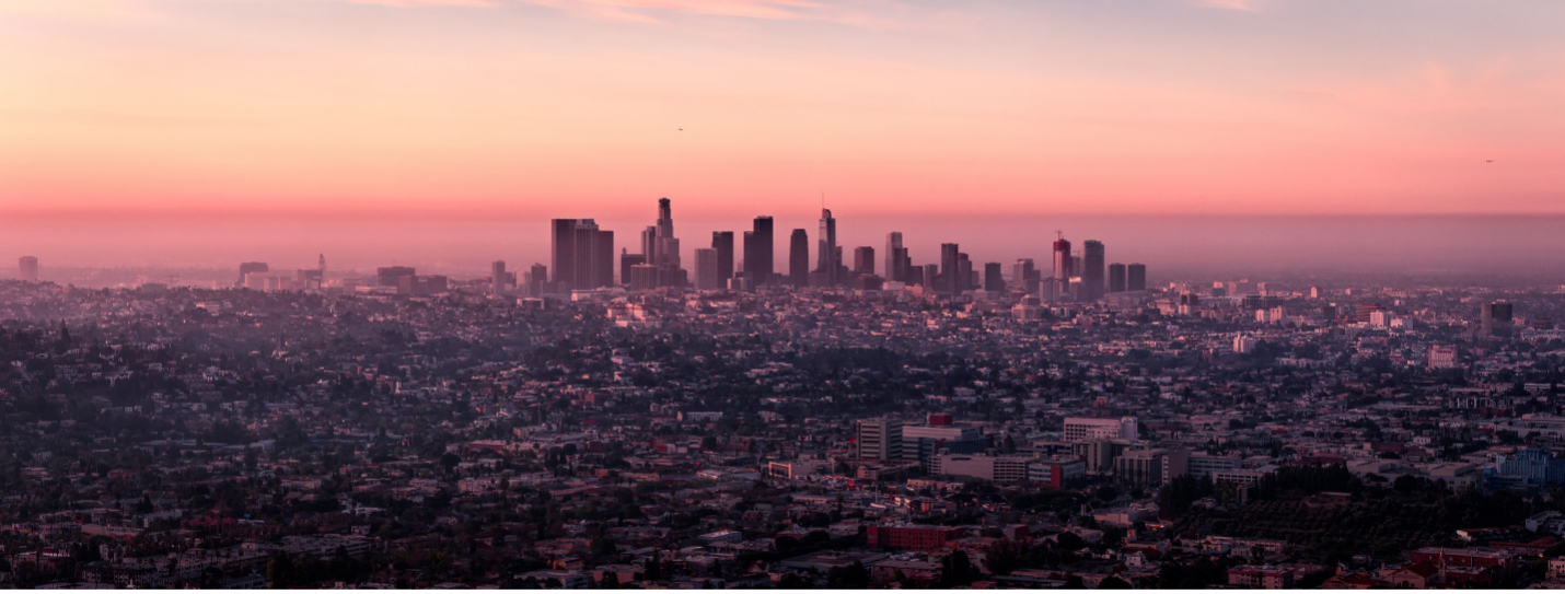 Photo of a hazy sunrise behind the LA landscape.
