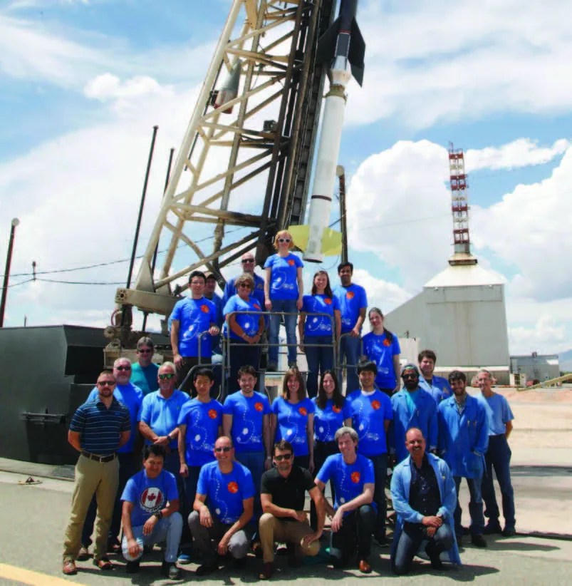 Photo of the 25 FOXSI team members wearing blue shirts and standing in front of the sounding rocket.