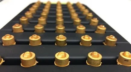 Photograph of small gold colored diodes on a black piece of hardware
