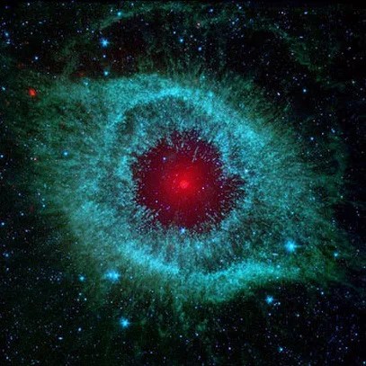 Cosmic starlet known as the Helix Nebula that resembles a teal eye with a red pupil.