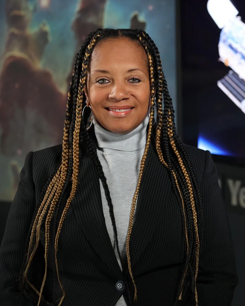 Headshot of Kim Hall standing in front of an Eagle Nebula image and the Hubble Space Telescope image