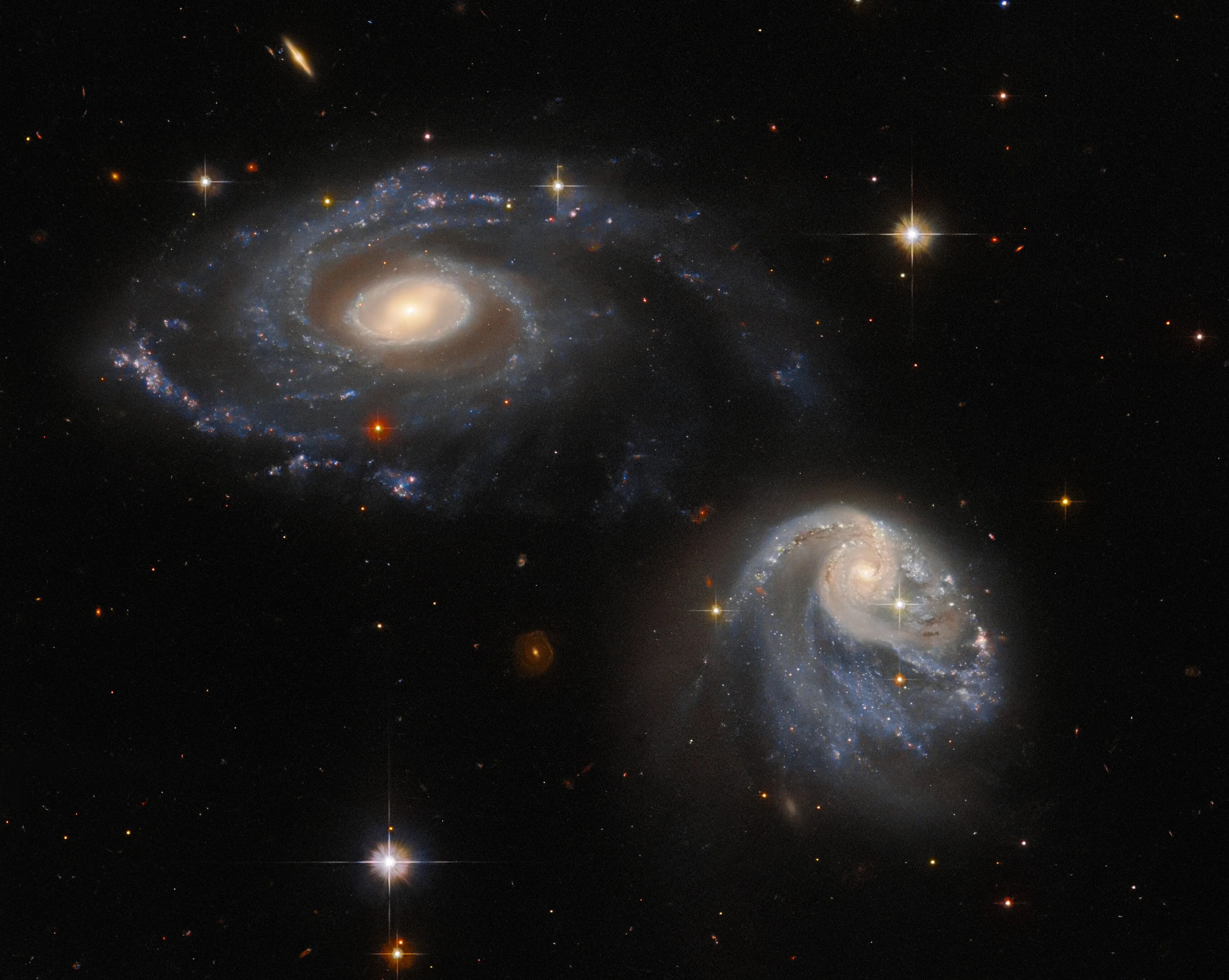 Two spiral galaxies, one at upper-left the other at lower-right, both are nearly face-on providing views of their spiral arms, background stars and galaxies