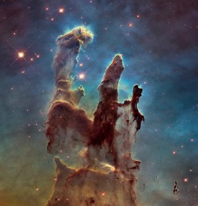 The famous Pillars of Creation revealed by the Hubble Space Telescope in high definition. Multiple pillars of brown gas and dust with potential stars in protruding fingertips, with a background of green and blue gas.