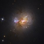 Dwarf galaxy with bright, blue stars, red and amber gas clouds, no visible spiral arms