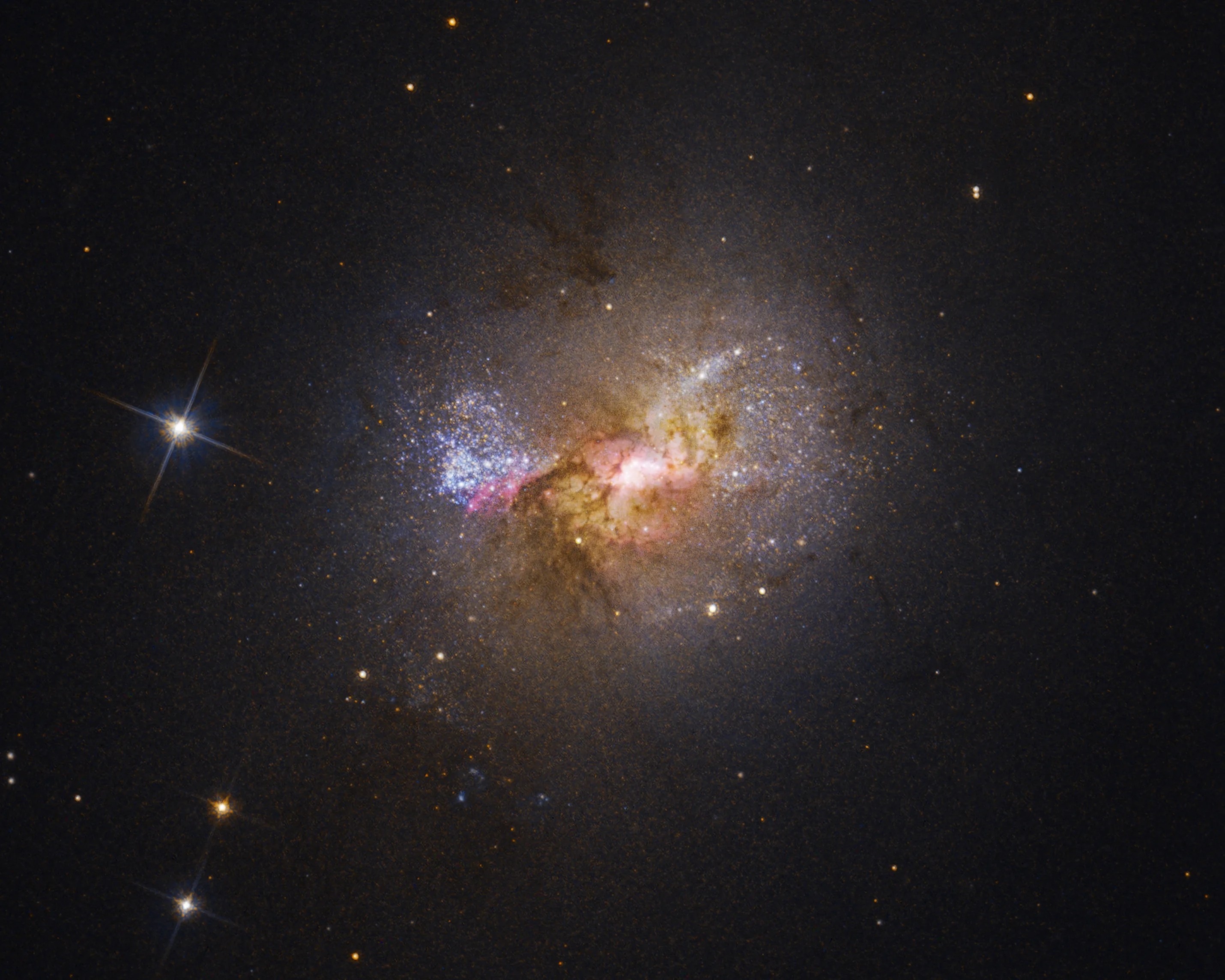 Dwarf galaxy with bright, blue stars, red and amber gas clouds, no visible spiral arms