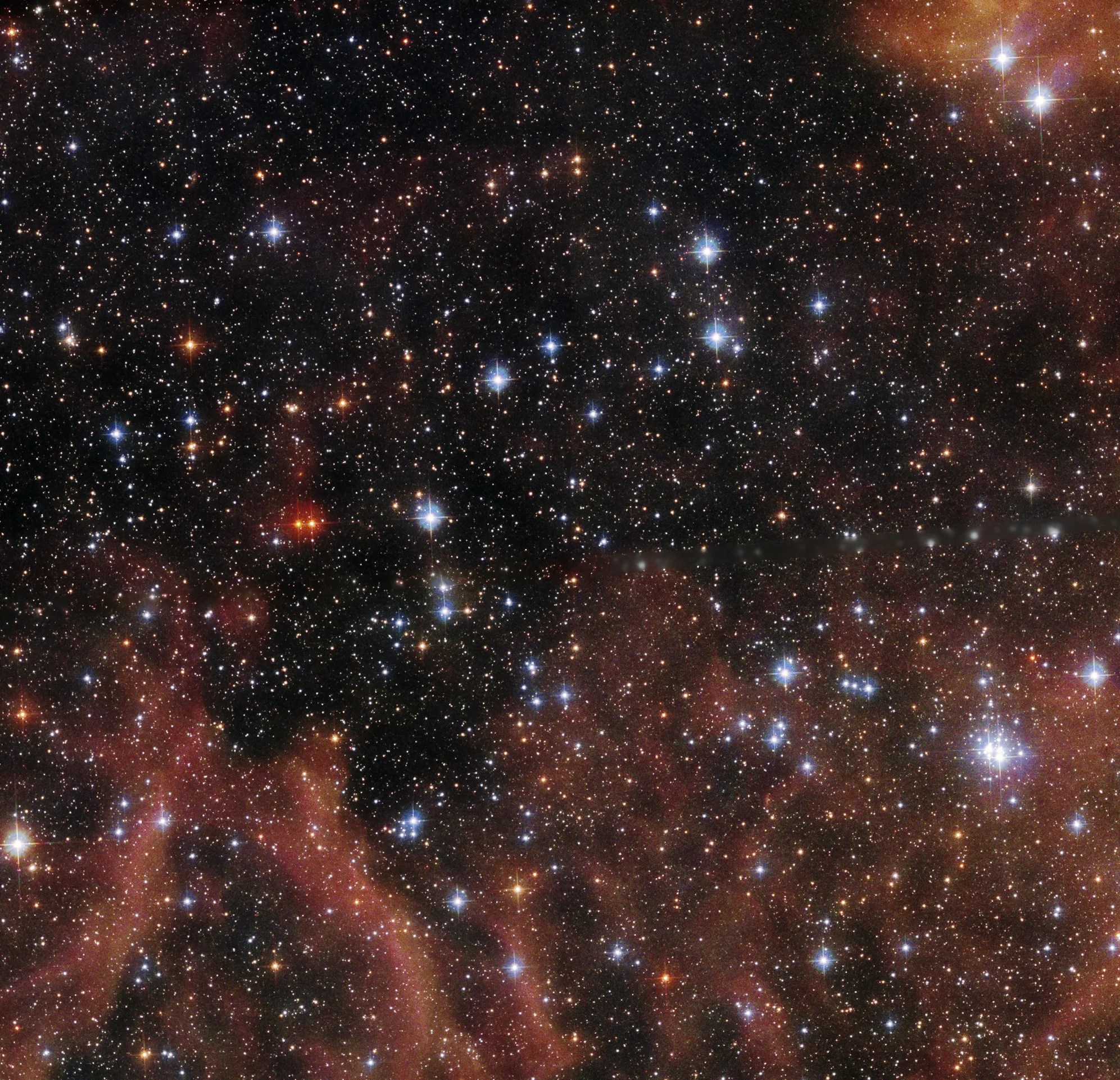 Bright. blue-white stars set against a black backdrop. rusty-red streams of gas and dust rise from the bottom of the image and in the upper right corner.