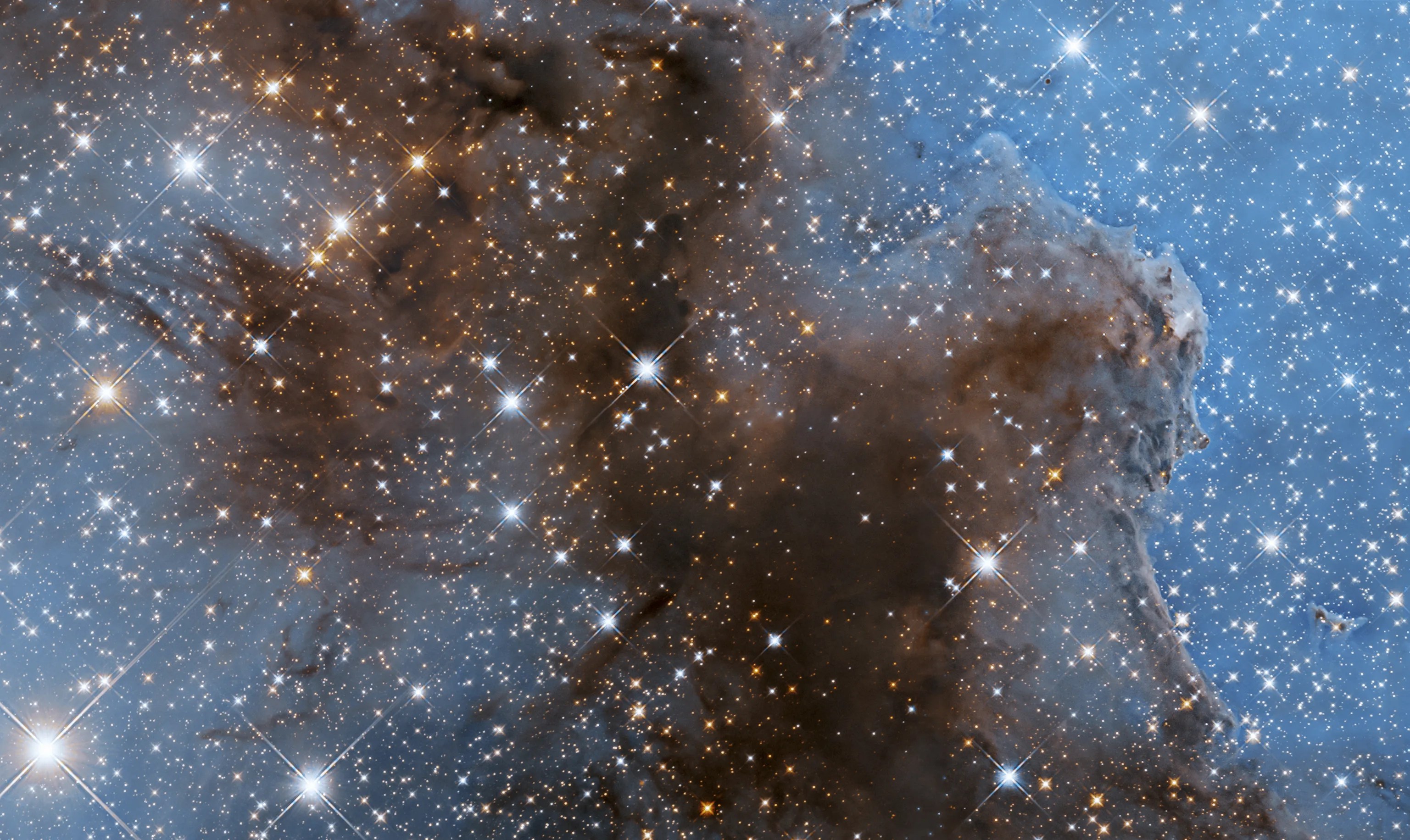 Dark, reddish-brown cloud fills the screen stretching from upper-left to filling the bottom of the image. Blue background is dotted with bright-white and yellow-orange stars.