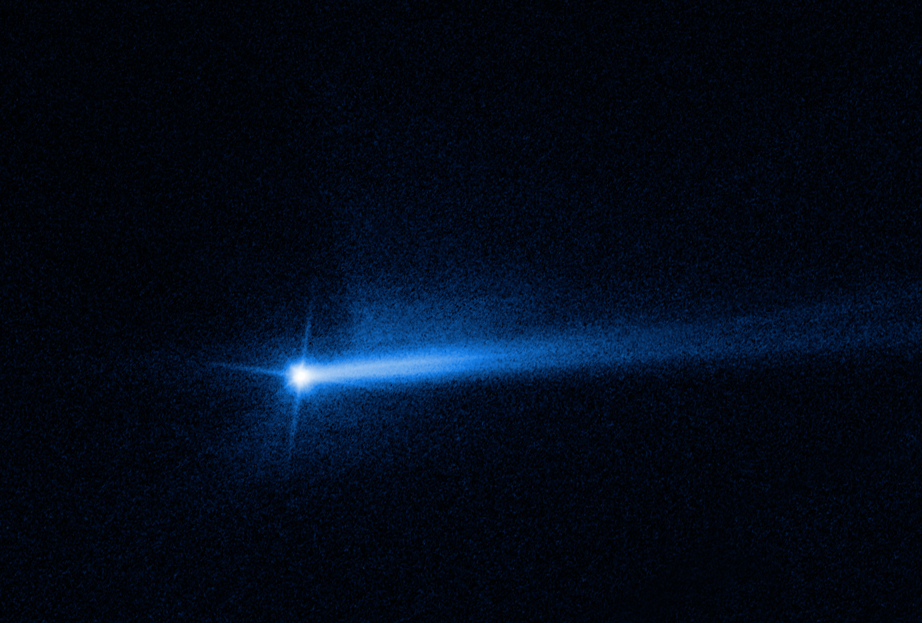Bright, blue-white tail extends to the right side of the image from a blue-white, star-like point just left of image center. dark black background.